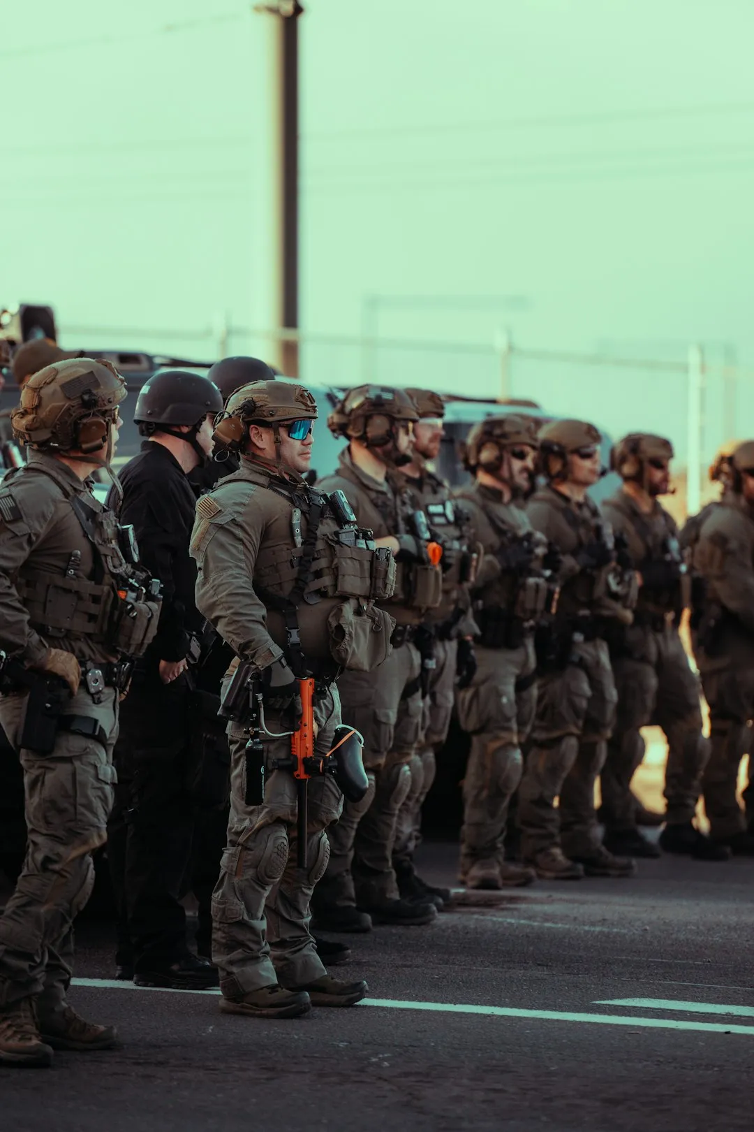 Armed soldiers stand in a row on a street.