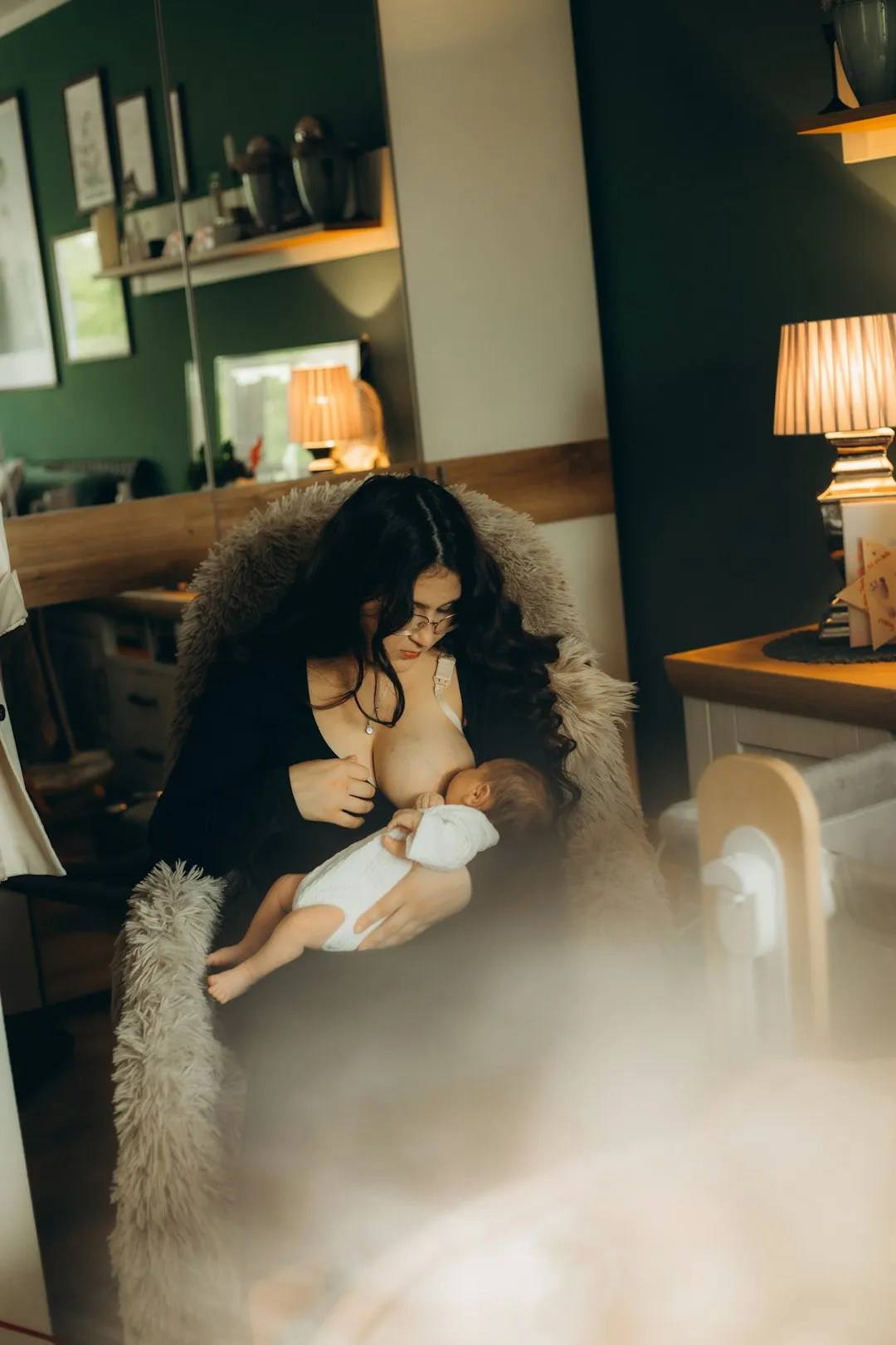 A woman breastfeeding her baby in a cozy room.